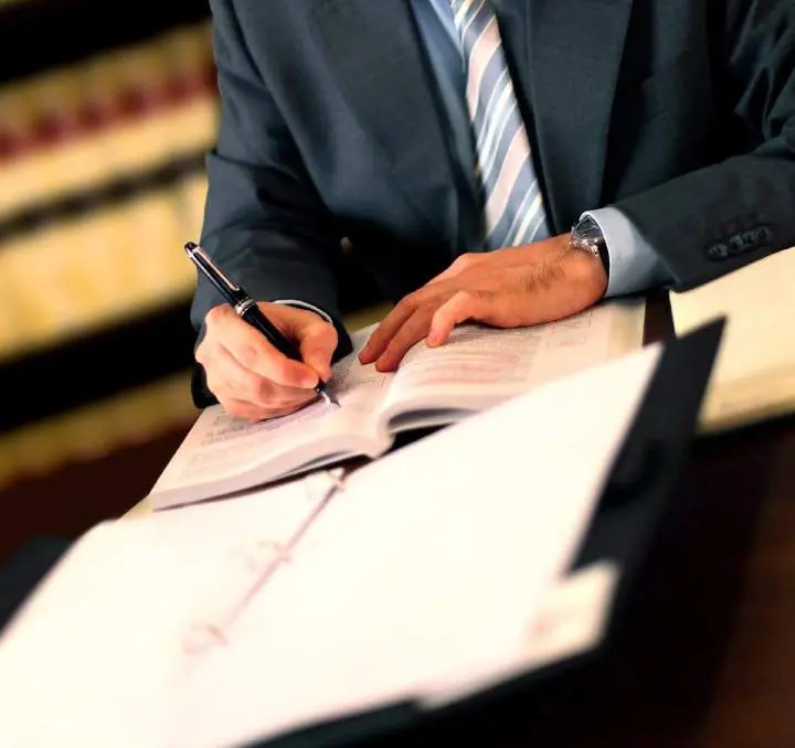 A man in suit and tie writing on paper.