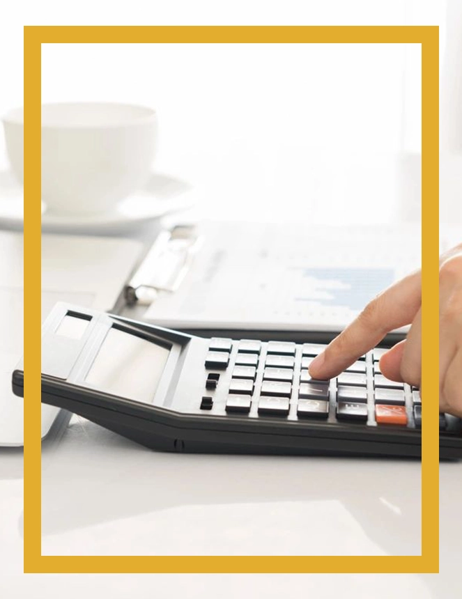 A person using a calculator on top of a desk.