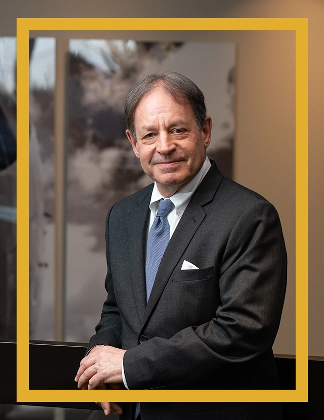 A man in suit and tie standing next to a yellow wall.